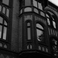 Schwarzweiß-Film-Foto einer Fassade eines alten Stadthauses mit Erker