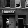 Schwarzweiß-Film-Foto eines Altbaus mit Durchfahrt und dem kaum noch leserlichen Schild des ehemaligen Club M darüber