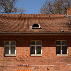 Roter Backsteinbau auf den 30er Jahren, mit teilweise altern, verwitterten Holzfenstern