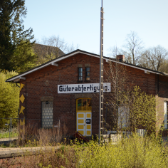 Ein rotes Backsteingeb&auml;ude mit seiner alten Beschriftung &bdquo;G&uuml;terabfertigung&ldquo;