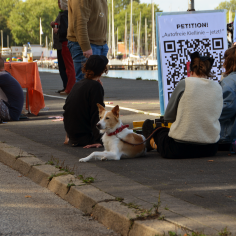 Menschen und ein Hund chillen auf dem Weg, ein QR-Code zur Petition daneben