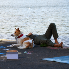 Ein Hund und ein Mann liegen an der Uferkante.