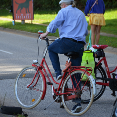 Menschen auf Fahrr&auml;dern und Rollern, ein rotes Vintage-Rad in der Bildmitte